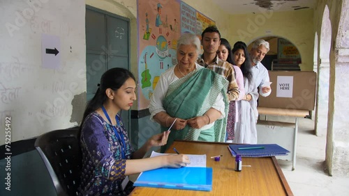 An Indian middle-aged government official verifying the details of the old lady - verification  village elections  identity proof. Candidates standing in queue for the completion of the verificatio... photo