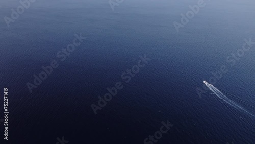 Epic drone shot of single luxury yacht crossing the ocean in the distance. Private boat charter in endless water. Space for text. Boats for rent in summer vacation. Idyllic tourist travel destination  photo