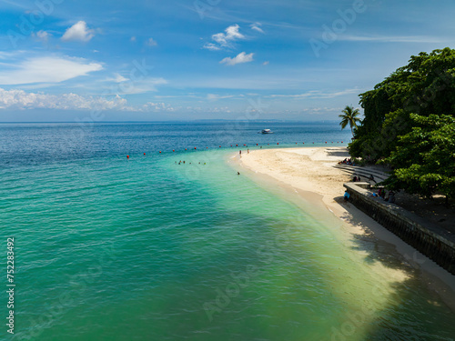 Beautiful sandy beach with waves at coastline. People and boat over the turquoise water. Kaputian Beach. Samal Island. Davao, Philippines. photo