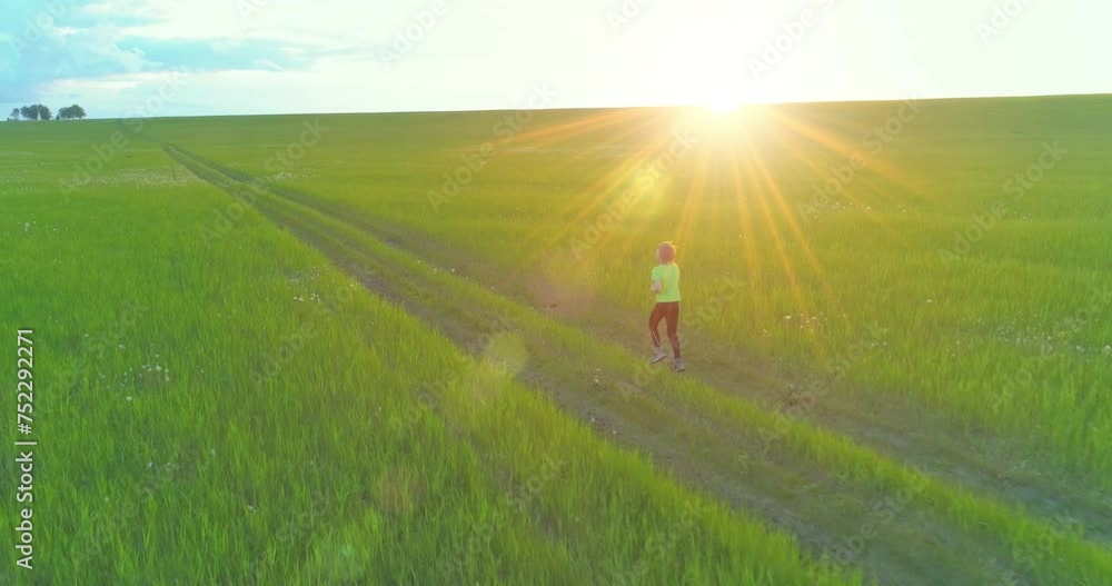 Aerial shoot of a sporty child runs through a wheat field. Evening sport training exercises at rural meadow. A happy childhood is a healthy way of life. Outdoor runing traning. Radial movement, sun Aerial shoot of a sporty child runs through a wheat field. Evening sport training exercises at rural meadow. A happy childhood is a healthy way of life. Outdoor runing traning. Radial movement, sun