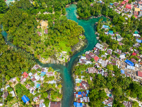 Blue clear water over the Bogac Cold Spring surrounded by villages and tropical forest. Surigao del Sur, Philippines. photo