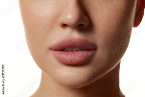 Cropped close-up image of beautiful female face  plump lips with nude lipsticks makeup isolated against white studio background. Lip augmentation. Concept of beauty  cosmetology  cosmetics  skin care