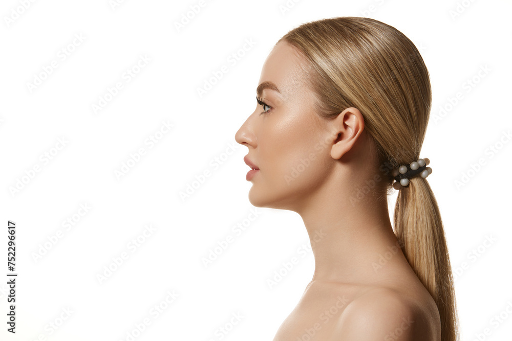 Obraz premium Side view portrait of beautiful young blonde woman with smooth skin isolated against white studio background. Face building, lifting effect. Concept of natural beauty, cosmetology, cosmetics