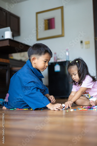 Asian sister and brother play together in cozy room wooden house floor