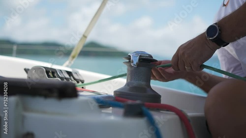 Sailor's hand on a winch of sailing boat. Close Up of Sailman Hands Unwinding Rope From Winch of Sailboat on Sunny