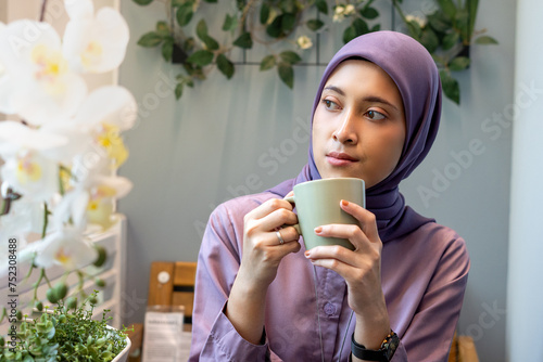 Photography Beautiful woman in hijab sitting on balcony holding green army glass looking rig