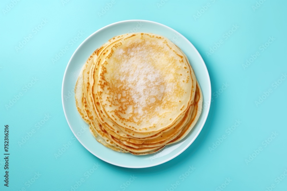 Thin pancakes or russian blini with sugar powder on blue background. Top view. Copy space.