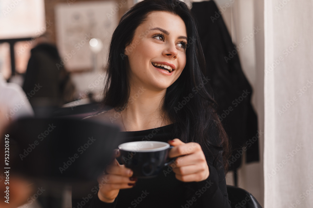 Brunette teen smiling and talking while drinking tea in cafe indoors. Girls have good conversation, gossiping, laughing. People, communication and friendship concept - smiling young women drinking tea Brunette teen smiling and talking while drinking tea in cafe indoors. Girls have good conversation, gossiping, laughing. People, communication and friendship concept - smiling young women drinking tea