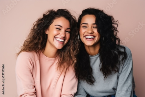Two Women Laughing Together on Pink Background