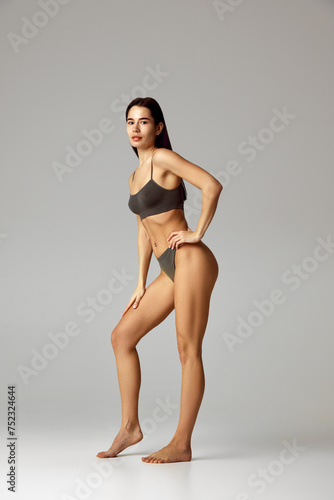 Beautiful, attractive woman posing in underwear against grey studio background. Female model with perfect body shapes. Concept of beauty, spa procedures, dermatology treatments, cosmetology care.