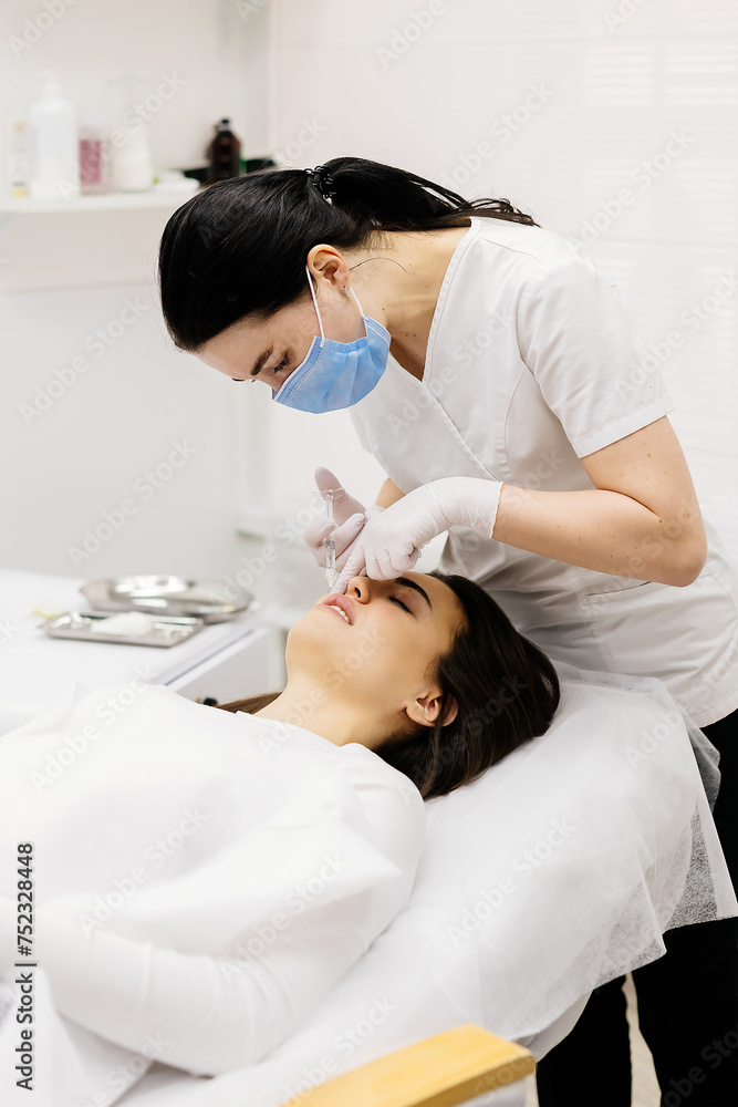 The procedure for lip augmentation and correction in a cosmetology salon. The specialist gives an injection to the patient's lips. Concept of cosmetology, cosmetic injections, and cosmetic surgery.
