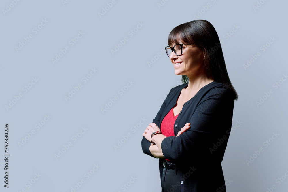 Profile portrait of mature confident smiling woman on gray background Profile portrait of mature confident smiling woman on gray background