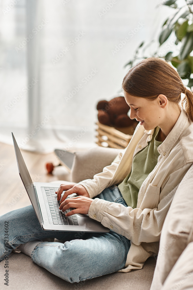 happy teenage girl focused on e-learning using her laptop and sitting on a comfortable sofa at home happy teenage girl focused on e-learning using her laptop and sitting on a comfortable sofa at home