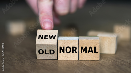 Hand turns wooden cube and changes the expression 'old normal' to 'new normal'.