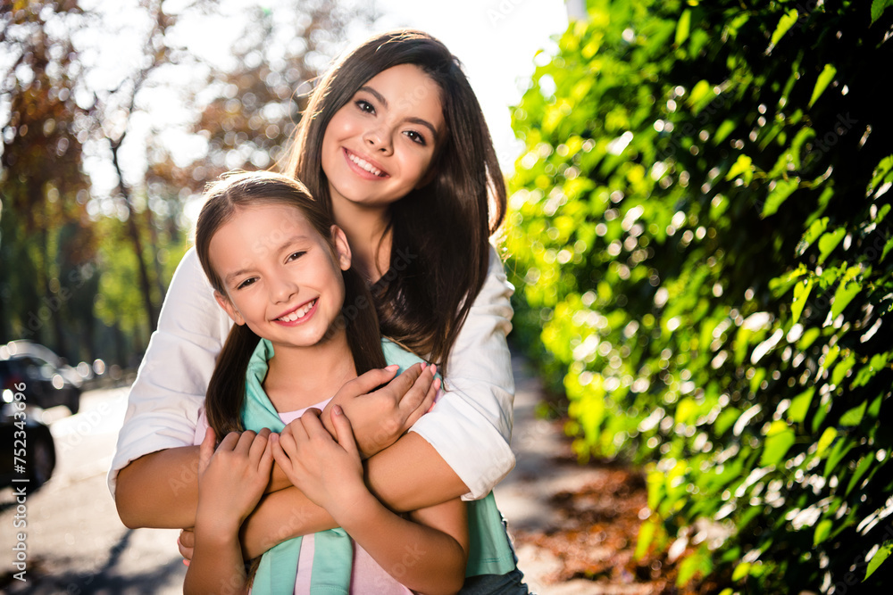 Photo of peaceful adorable girls beaming smile hugging enjoy free time walk sunny weather city center outside Photo of peaceful adorable girls beaming smile hugging enjoy free time walk sunny weather city center outside