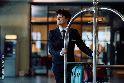 Εκτύπωση καμβά Happy hotel attendant pushing luggage cart through the hallway.