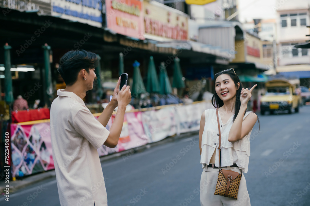 Obraz premium Young happy Asian couple tourist backpackers enjoy traveling in the local market.