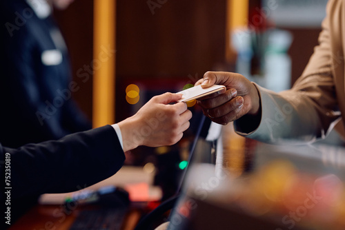 Close up of receptions giving cardkey to guest at hotel front desk. photo