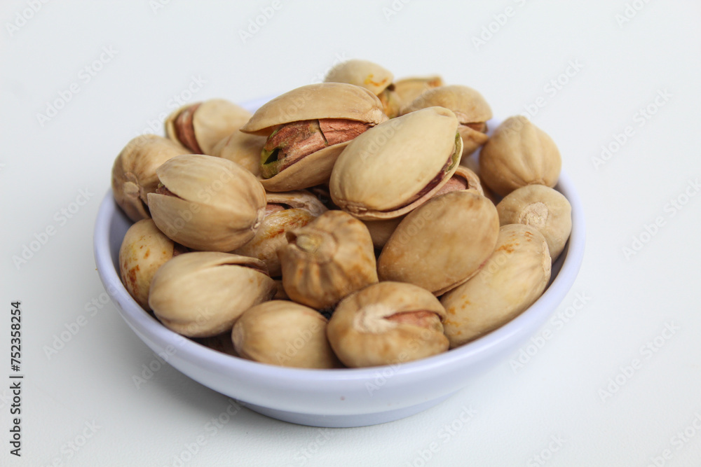 Salted pistachio on the small white bowl, isolated on white background
