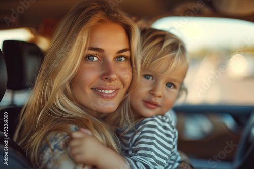 Motherhood lifestyle, parenthood. Portrait of a beautiful smiling blonde mother with her child in car, mom driver with a little boy behind the wheel © Sergio