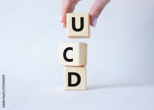 UCD - User Centered Design. Wooden cubes with word UCD. Businessman hand. Beautiful white background. Business and User Centered Design concept. Copy space.