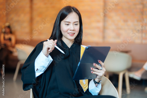 Asian female lawyer wearing a legal suit Prepare for the promotion exam to become a court judge to decide cases of plaintiffs and defendants. Happy reading exam questions on tablets in the cafe.