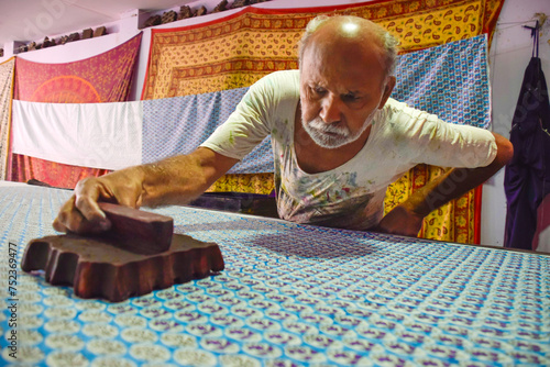 Artisan stamping patterns in ink on traditional Indian textiles as colorful sari