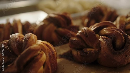 Freshly baked cinnamon rolls close-up illuminated by the morning sun. Hot Scandinavian buns lie on a table in a bakery and cool down, steam rising above them. Morning pastries, bakery.