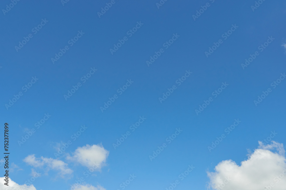 White fluffy clouds in the sky. Blue sky and cloud cover on a sunny summer day. Empty background, copy space