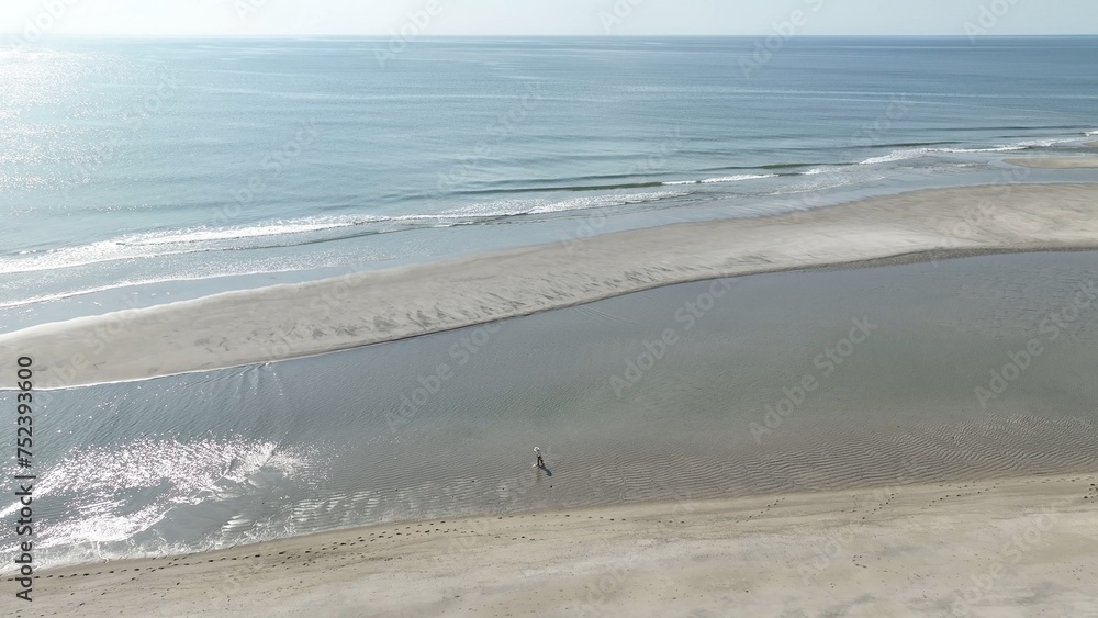 Aerial drone view of beach with sand and ocean with waves breaking in the gentle surf during summer in Pawleys Island, South Carolina vacation destination for family 
