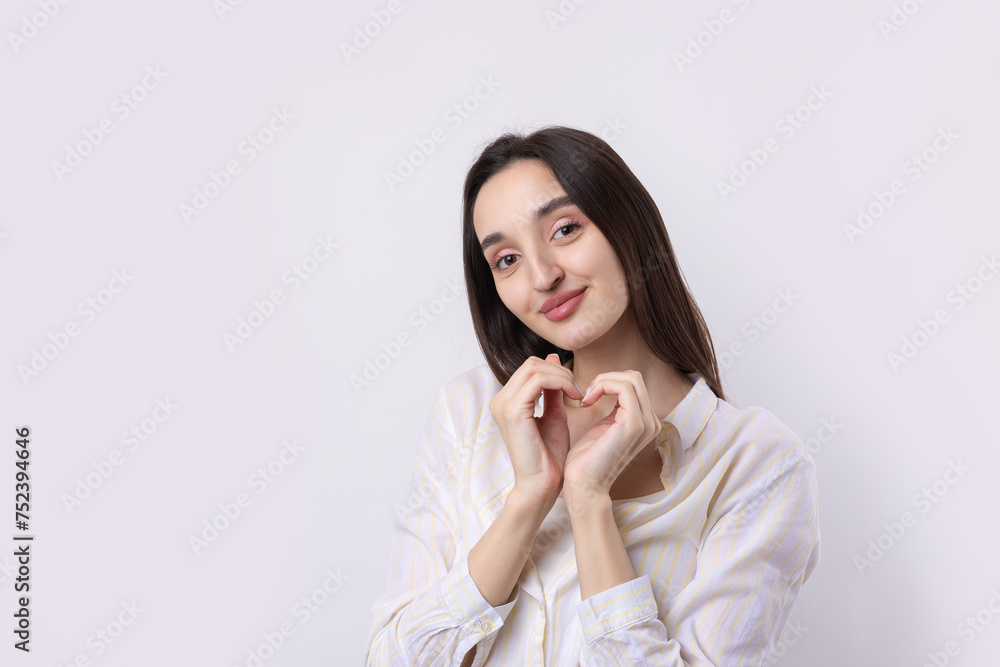 Portrait of a smiling young woman showing heart gesture with her fingers isolated over white background Portrait of a smiling young woman showing heart gesture with her fingers isolated over white background