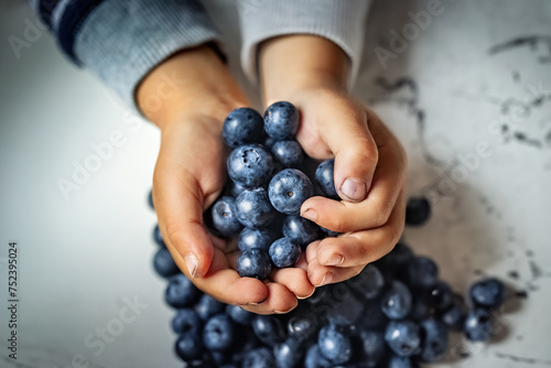 Close-up of childs hands holding fresh blueberries