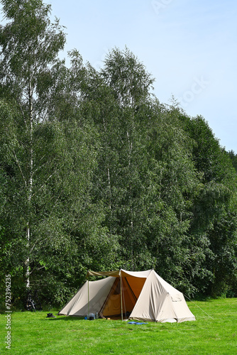 Campsite in the Belgian Ardennes with a canvas shelter consisting of sheets of cotton fabric on grass