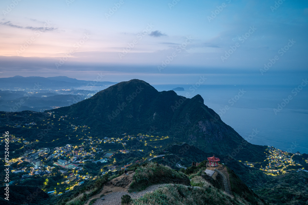 Fototapeta premium At dusk, admire the valley's villages and the sea from the top of the mountain. Teapot Mountain Hiking Trail in Ruifang District, New Taipei City. Taiwan.