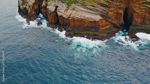 Fototapeta Naklejka Na Ścianę i Meble -  Foaming waves crashing rocky coastline aerial. Wild sea washing reef rock cliffs