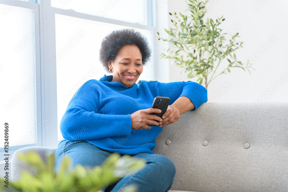 Black woman using cellphone on living room at home Black woman using cellphone on living room at home
