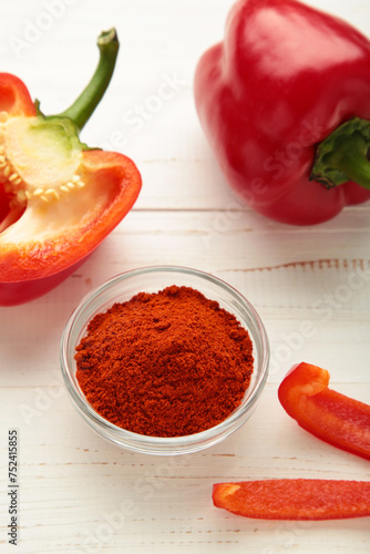 Paprika powder in plate with fresh red pepper on white background. Vertical photo
