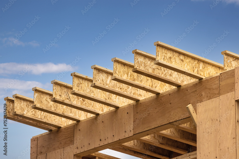 Fototapeta premium Engineered wood joists or rafters forming the roof of a house under construction