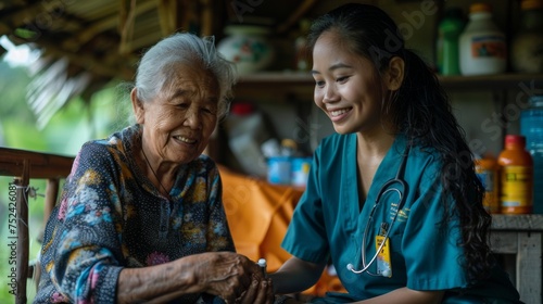 Community care concept: A friendly Asian nurse giving medicine to senior woman at home © Moesy-TM