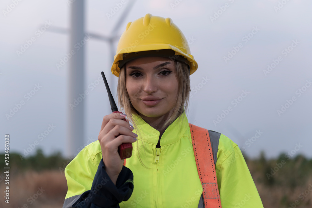 portrait of a worker using radio communication. Engineers discussing against turbines on wind turbine farm. portrait of a worker using radio communication. Engineers discussing against turbines on wind turbine farm.