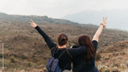 Back view of mother and daughter with arms raised in a victory sign, celebrating on a hike