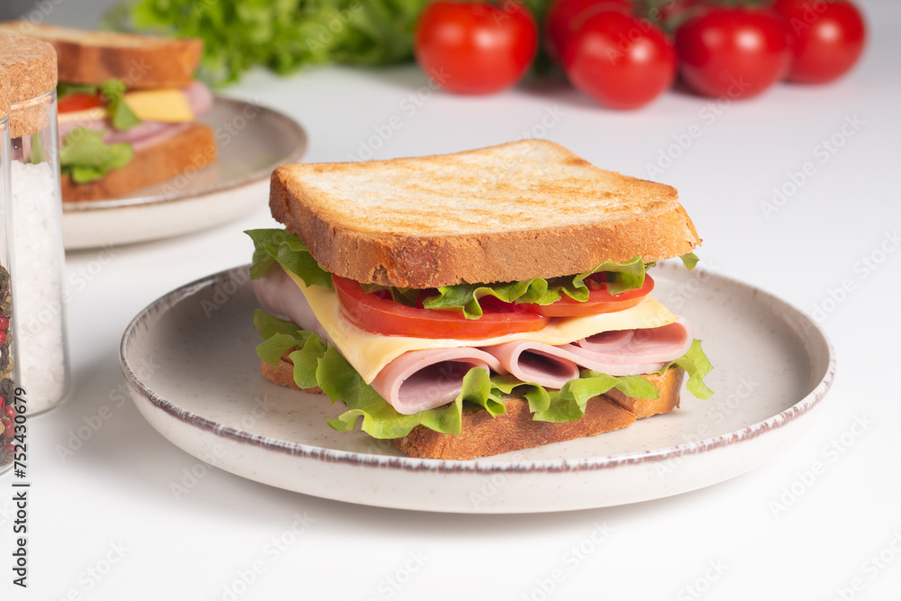 Close-up of two sandwiches with bacon, salami, prosciutto and fresh vegetables on rustic wooden cutting board. Club sandwich concept Close-up of two sandwiches with bacon, salami, prosciutto and fresh vegetables on rustic wooden cutting board. Club sandwich concept