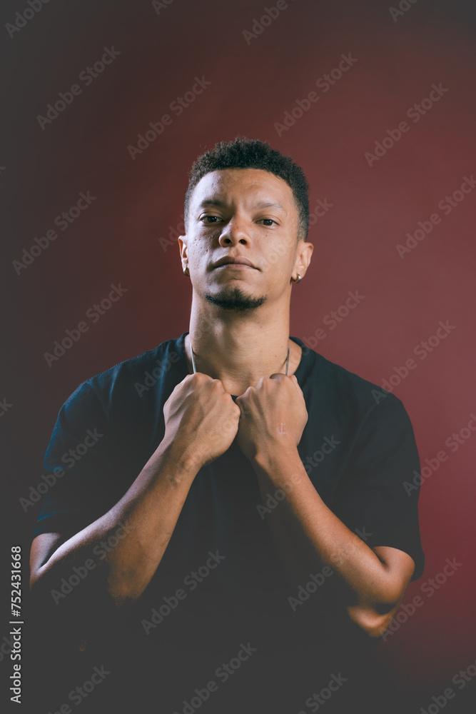 Portrait of serious looking young African American man holding on to neck chain