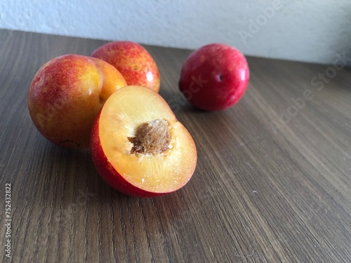 Red plum in bowl on a wooden background with copy space
​ photo