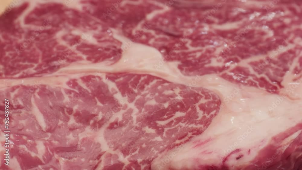 Fresh marbled beef with pepper, salt and rosemary close-up macro. Preparation to cook juicy steak on grill. Premium organic raw wagyu meat Fresh marbled beef with pepper, salt and rosemary close-up macro. Preparation to cook juicy steak on grill. Premium organic raw wagyu meat