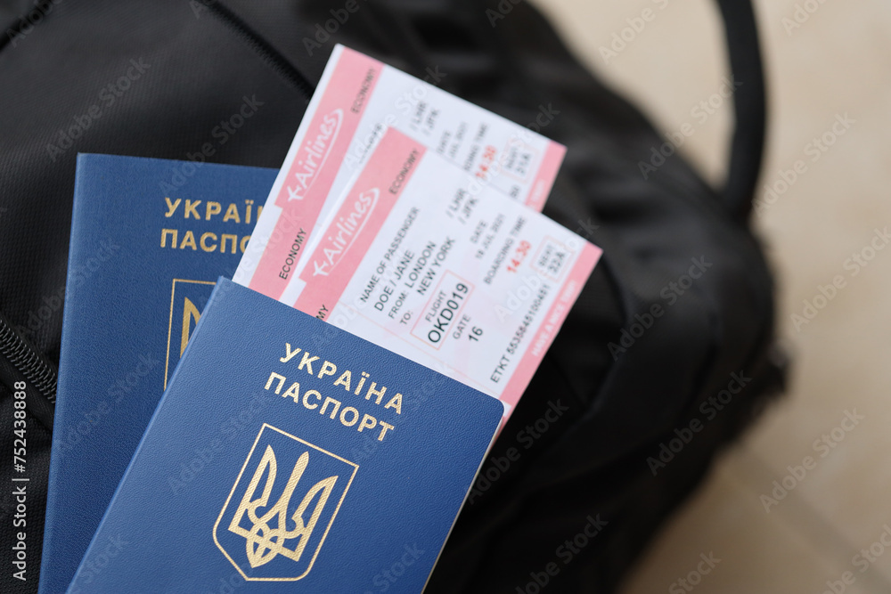 Obraz premium Two ukrainian biometrical passports with air flight tickets on black touristic backpack close up