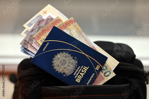 Blue Brazilian passport with money and airline tickets on touristic backpack close up. Tourism and travel concept photo