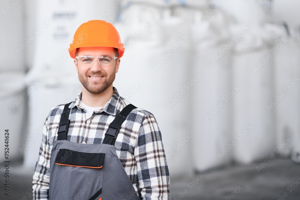 Portrait of man loader in uniform near big bag of coffee beans or wheat, nuts in warehouse of manufacturing factory Portrait of man loader in uniform near big bag of coffee beans or wheat, nuts in warehouse of manufacturing factory