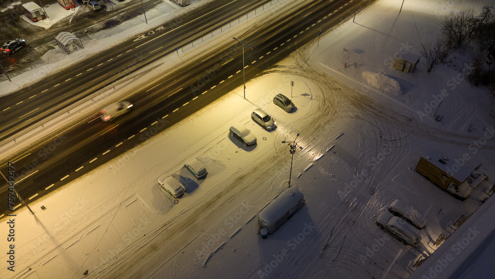 Drone photography of a small parking lot and cars covered in snow during winter night Drone photography of a small parking lot and cars covered in snow during winter night