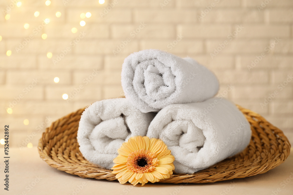 Rolled terry towels and flower on white table near brick wall indoors, space for text Rolled terry towels and flower on white table near brick wall indoors, space for text